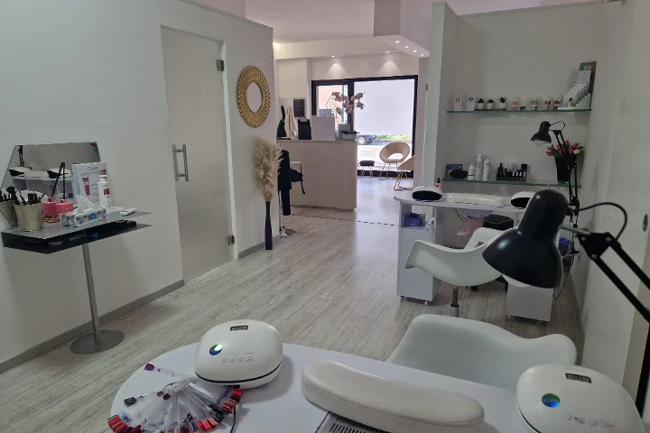 Ρεσεψιόν και χώρος μανικιούρ στην Estetica Francesca στο Olbia με στρογγυλό καθρέφτη τοίχου και γυάλινα ράφια με προϊόντα ομορφιάς.