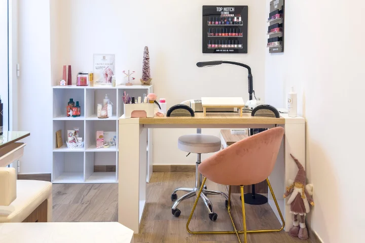Θέση μανικιούρ στο Gd Beauty Clinc di Giulia Delogu στο Alghero με ροζ βελούδινη καρέκλα και εκθετήριο βερνικιών Top Notch.