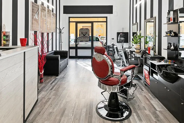 Κόκκινη vintage πολυθρόνα μπαρμπέρη στο Hair 99 στο Alghero, με τους χαρακτηριστικούς ασπρόμαυρους τοίχους σε ρίγες.
