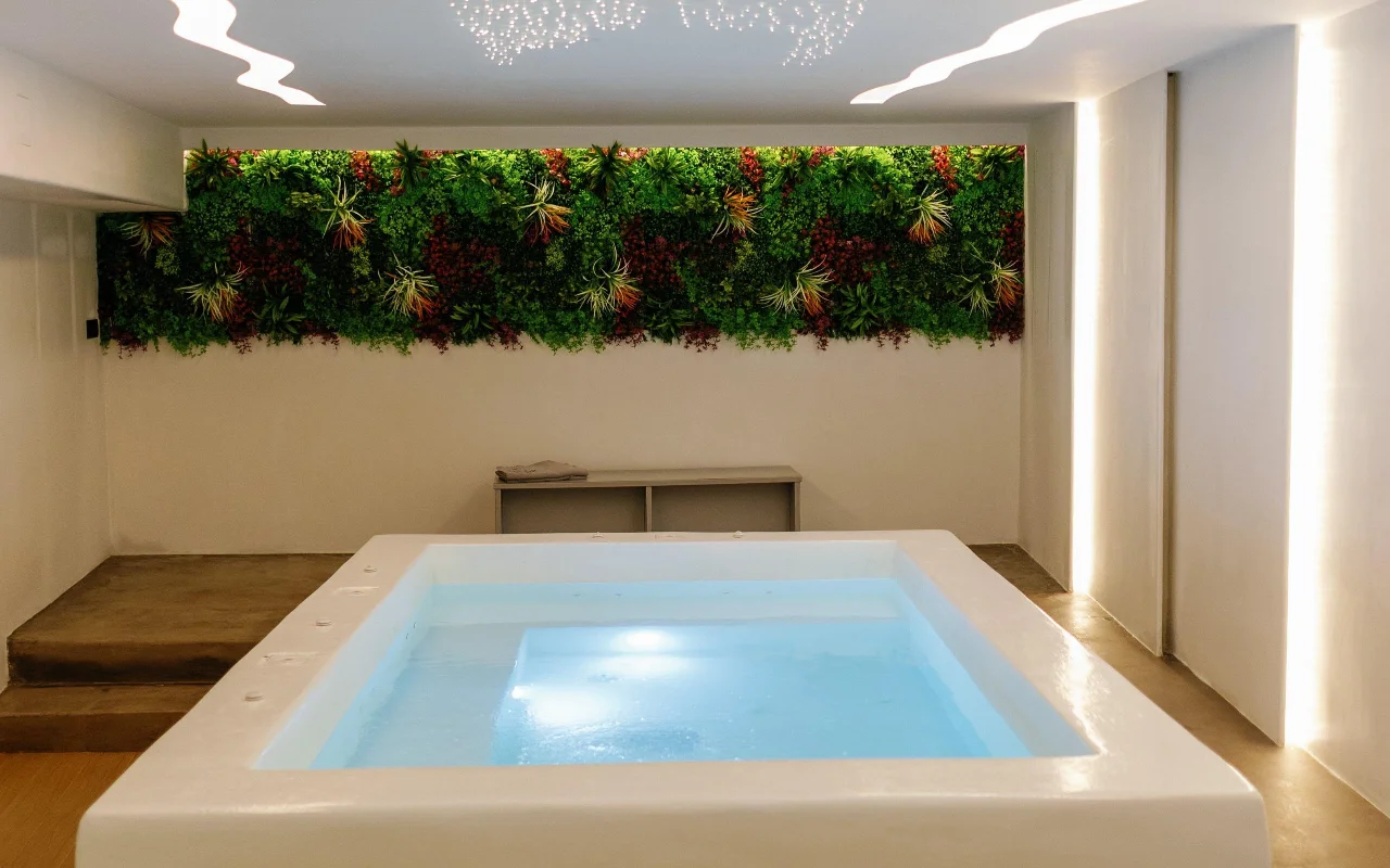 Η πισίνα υδροθεραπείας στο Liana Spa Therapy στη Νάξο, απαλά φωτισμένη από μέσα, κάτω από έναν πολύχρωμο ζωντανό τοίχο με διατηρημένα φυτά και μια οροφή διάσπαρτη με μικροσκοπικά αστέρια-φωτάκια.