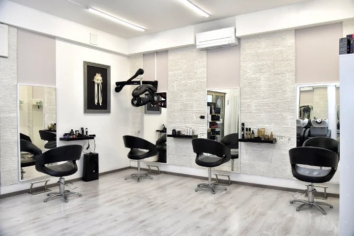 Μοντέρνες θέσεις styling στο Sp Beauty di Serena Pinna κοντά στις παραλίες του Pittulongu στο Olbia, με μαύρες καρέκλες και μεγάλους καθρέφτες.
