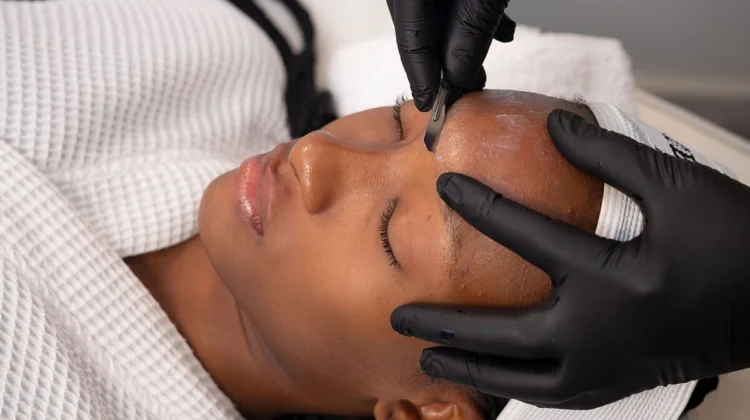 Κοντινό πλάνο μιας αισθητικού που κάνει dermaplaning σε μια πελάτισσα σε κέντρο αισθητικής